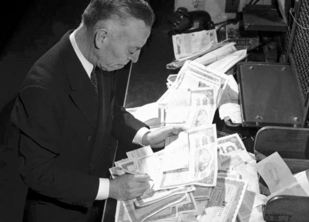 Wall Street clerk sorting through piles of paper stock certificates during the 1960s paperwork crisis